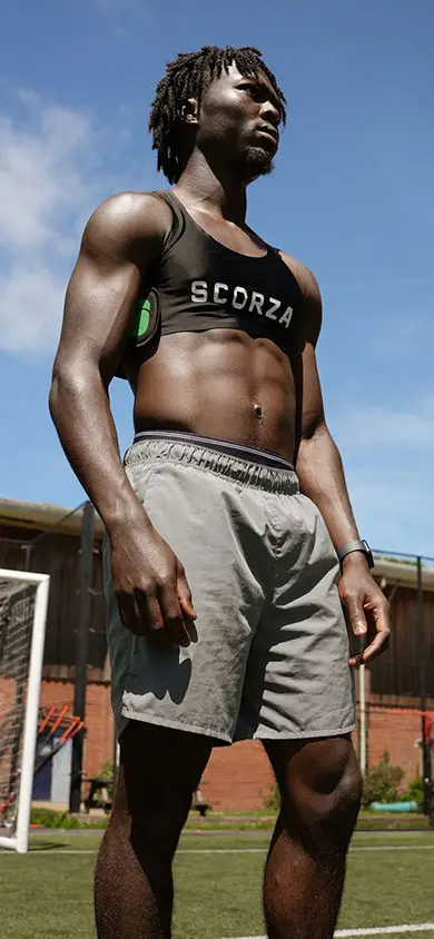 Footballer on a pitch wearing the black Scorza GPS vest and a smartwatch